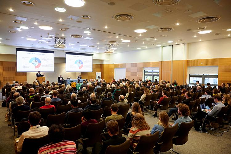 wide shot of the auditorium from the back showing the audience and projection screens