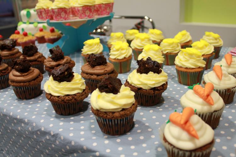 A close up of chocolate and carrot cake cupcakes on a blue polka dot table cloth at a bake sale raising funds for the Euan MacDonald Centre