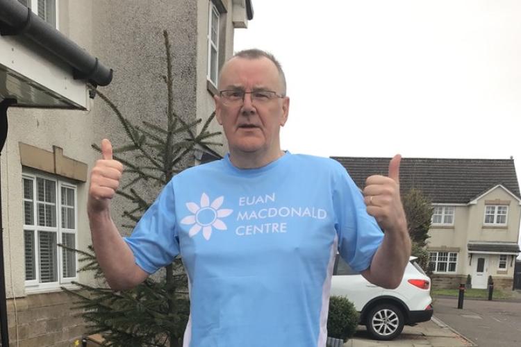 David Thomson, wearing a Euan MacDonald Centre T-shirt, is standing and giving both thumbs up