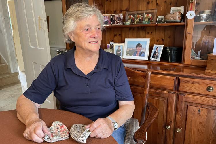 A picture of Doreen sitting in her kitchen with some of her face-masks
