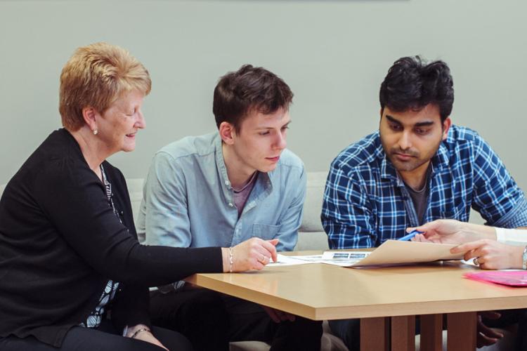 Four people sat round a table talking through news items paperwork