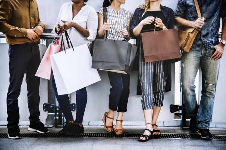 Mid shot (above knees, below elbows) of five people in casual wear, carrying shopping bags and shoulder-bag