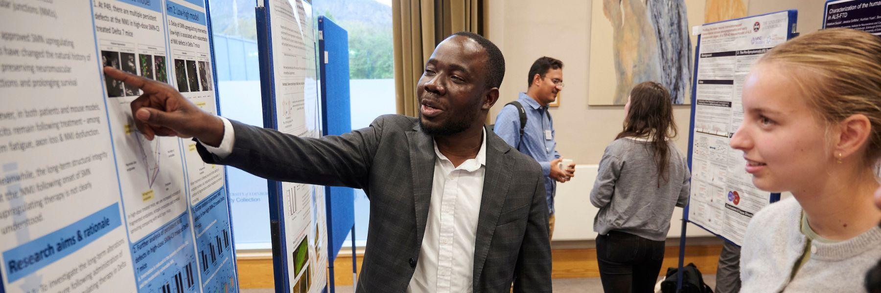 Postdoc researchers showing a poster presentation of their research