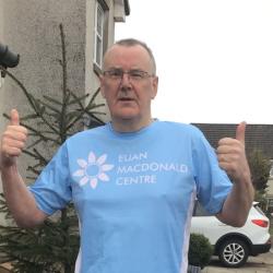 David Thomson, wearing a Euan MacDonald Centre T-shirt, is standing and giving both thumbs up